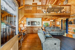 Ein großzügiges Blockhauskabinen-Interieur mit einer Holztreppe, einem großen Sofa und einem Essbereich.