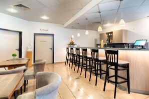 Ein Restaurant mit Barbereich, verschiedenen Sitzgelegenheiten und einem modernen, sauberen Interieur.