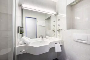Ein modernes Badezimmer mit einem großen Spiegel, zwei Waschbecken, einem Handtuchhalter und einer Duschkabine.