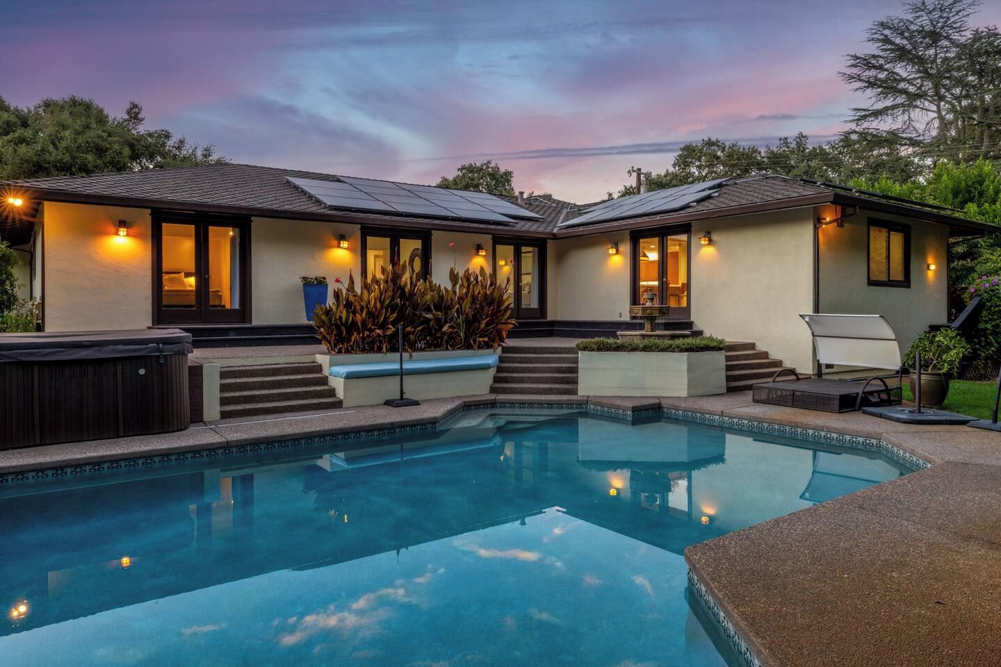 Une maison à deux étages dotée d’une piscine, d’un éclairage extérieur et d’un jacuzzi.