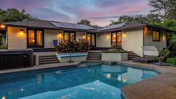Une maison à deux étages dotée d’une piscine, d’un éclairage extérieur et d’un jacuzzi.