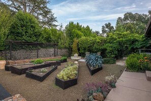 Un jardin avec des plates-bandes surélevées, un mur en pierre et une grande variété de plantes.