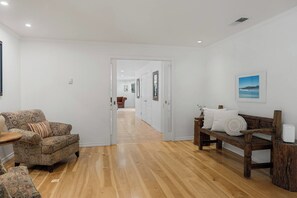 A hallway with a patterned sofa, a wooden bench, and a door leading to another room. - Blossom Villa-pool+sanctuary+ minutes to wineries (Sonoma)