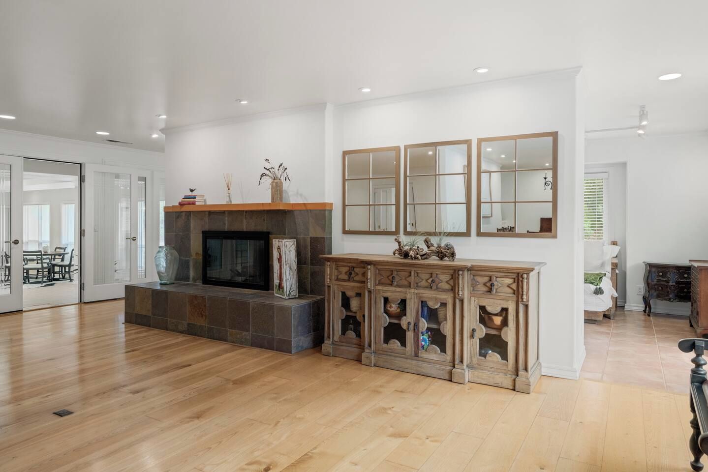 Amplia sala de estar con chimenea, un espejo grande y un mueble de madera.