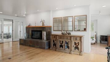 Amplia sala de estar con chimenea, un espejo grande y un mueble de madera.