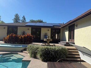 A residential property with a swimming pool, solar panels, a fountain, and a well-maintained garden.