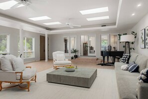 A spacious living room with a piano, a white armchair, and a grey sofa. - Blossom Villa-pool+sanctuary+ minutes to wineries (Sonoma)