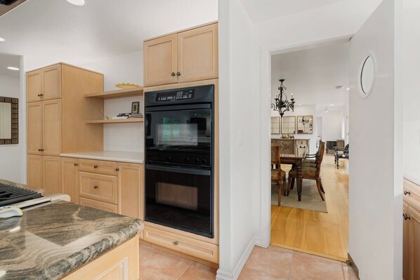 A kitchen with wooden cabinets, a built-in oven, and a marble countertop.