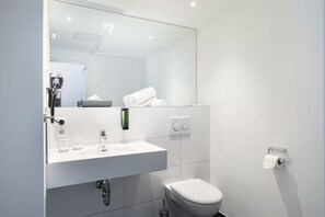 Ein modernes Badezimmer mit Waschbecken, Spiegel, Toilette und Handtuchhalter.