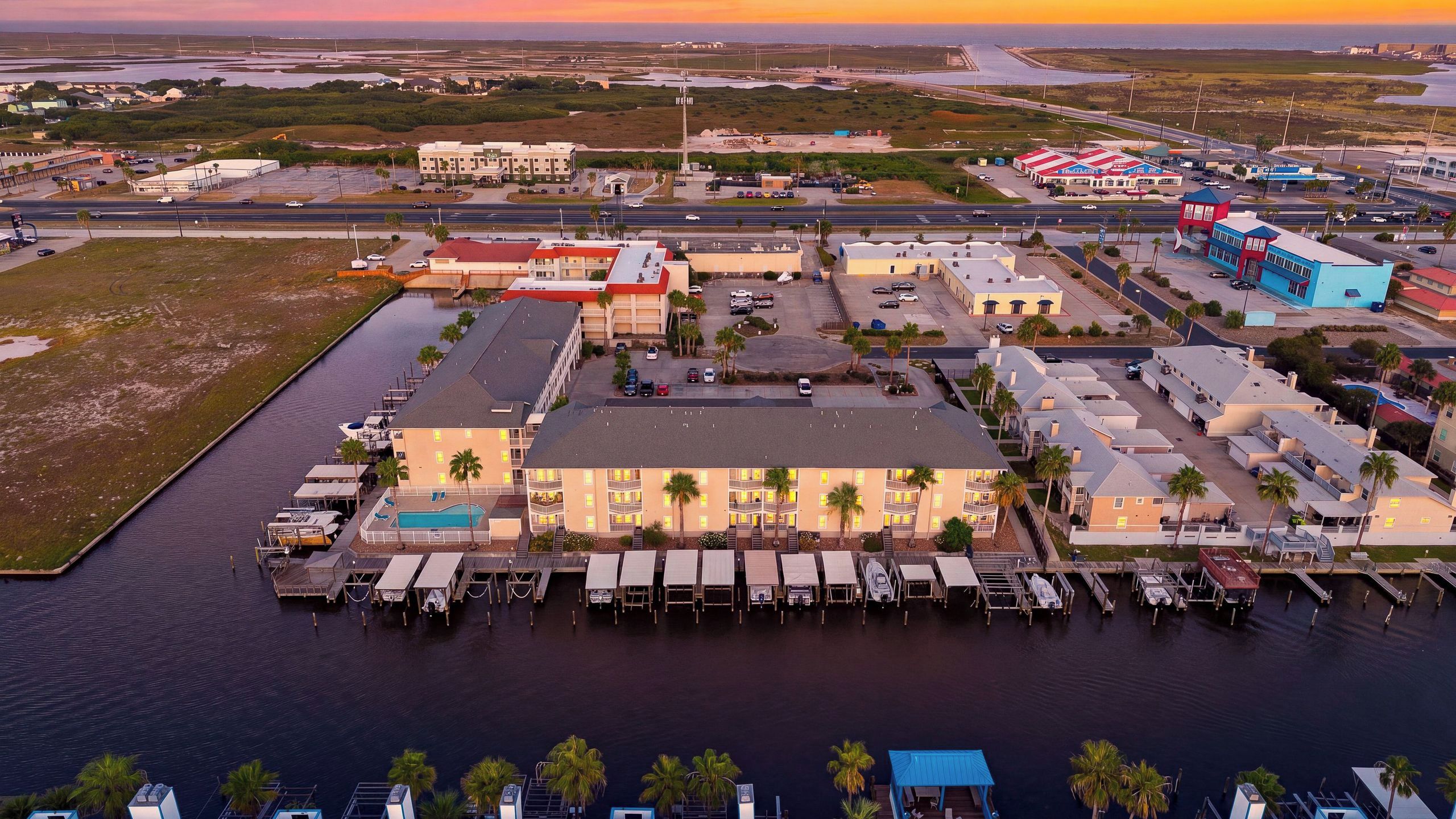 A waterfront hotel with multiple buildings, a marina, and a parking area.