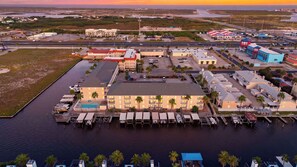 Un hotel frente al agua con varias edificaciones, un puerto deportivo y un estacionamiento.