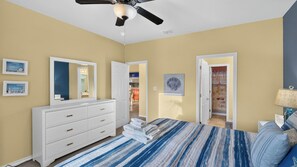 A bedroom with a bed, dresser, and a ceiling fan. There are doors leading to other rooms. - Paradise Found by Avantstay Waterfront Retreat Private Boat Slip + Shared Pool North Padre (Corpus Christi)