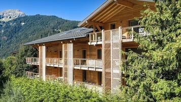 Eine Holzchalet mit mehreren Balkonen vor einer Bergkulisse.