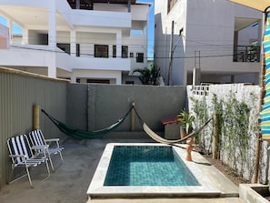 A swimming pool with a hammock and lounge chairs, surrounded by a high wall and vegetation. - Porto de Galinhas Maraca 50m Mar Loctemp (Ipojuca)