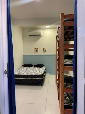 A room with a bed, a bunk bed, a wall-mounted air conditioner, and two small framed pictures. - Porto de Galinhas Maraca 50m Mar Loctemp (Ipojuca)