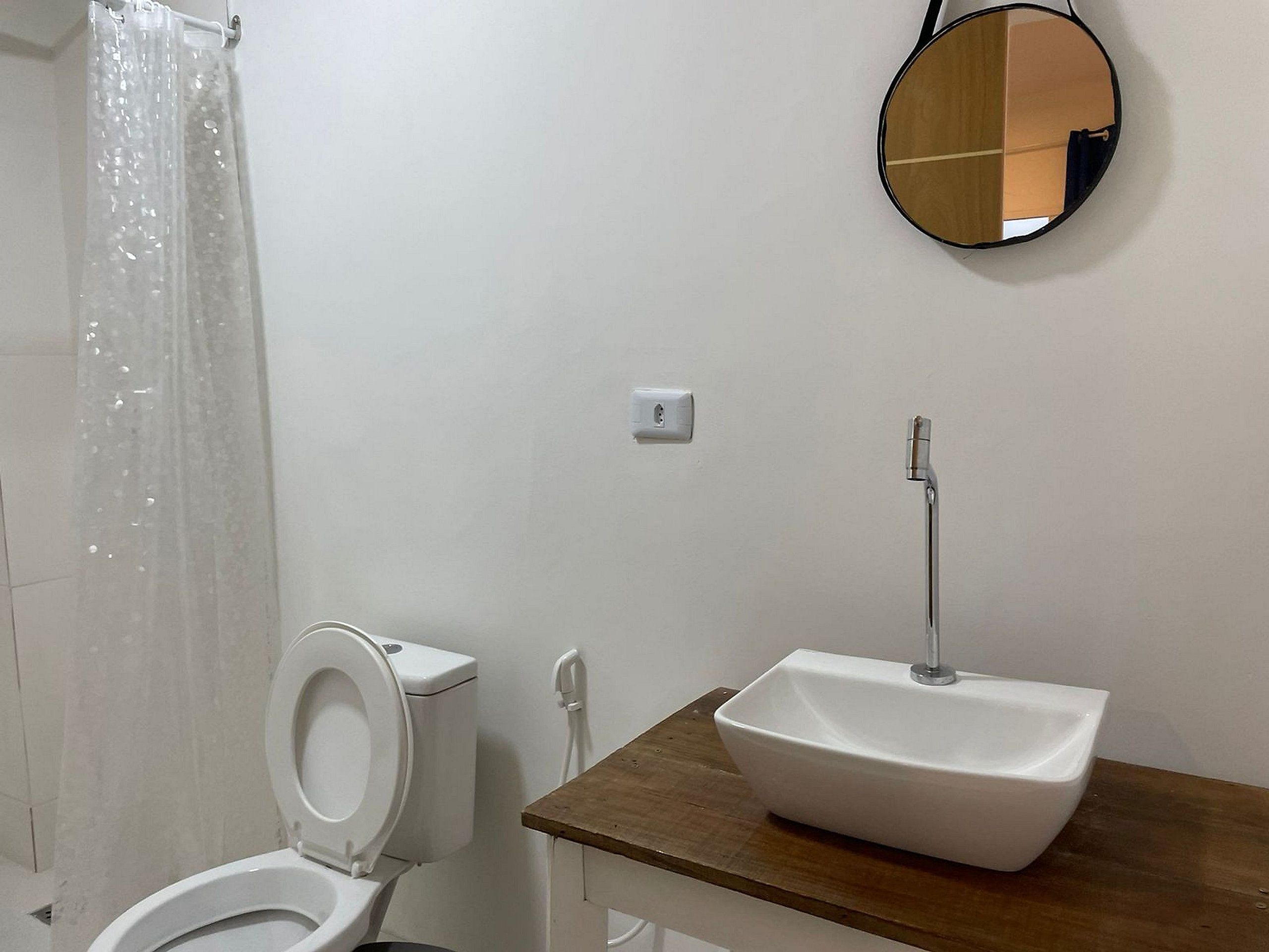 Une salle de bain équipée de toilettes, d’un lavabo, d’un miroir et d’un rideau de douche.