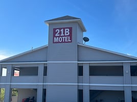 Un motel con un letrero llamativo que dice '21B MOTEL' en el techo.
