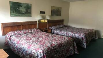 Een hotelkamer met twee bedden, een houten hoofdbord, een nachtkastje met lampen en twee schilderijen aan de muur.
