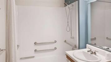 Une salle de bain avec une douche, un lavabo et un miroir.