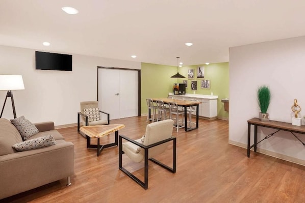 A modern living room with a sofa, armchair, coffee table, and dining area with chairs and a table.