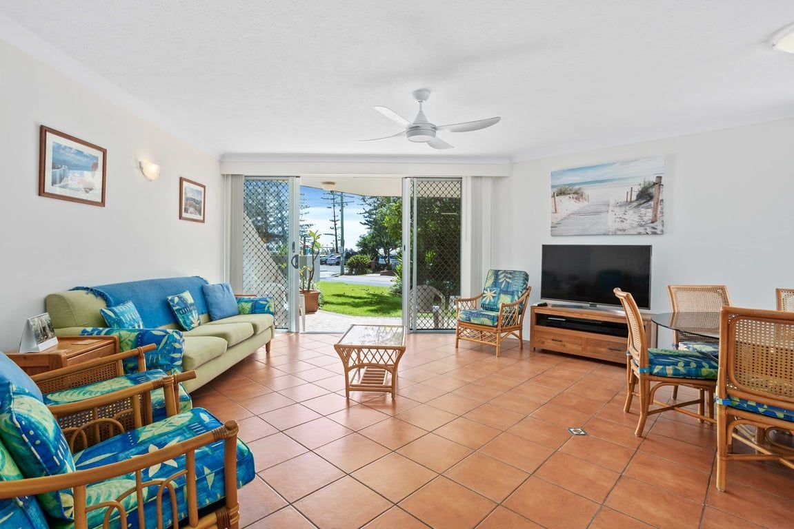 A living room with a sofa, chairs, a TV, and a balcony with a view.
