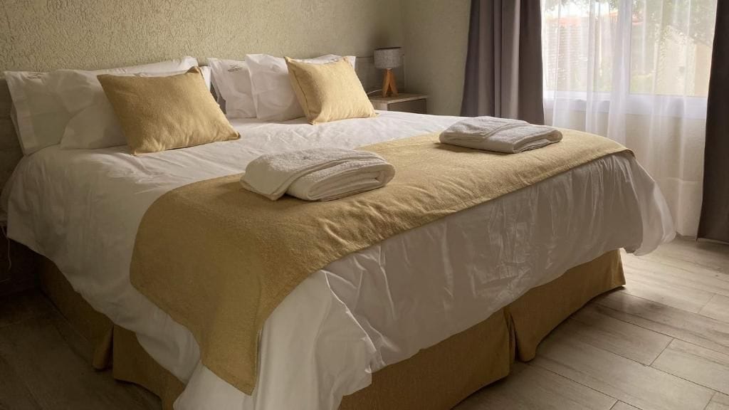 A hotel room with a large bed, a bedside table, and a window with curtains.