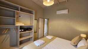 Una habitación de hotel con cama, armario, espejo y puerta que da a otra habitación.