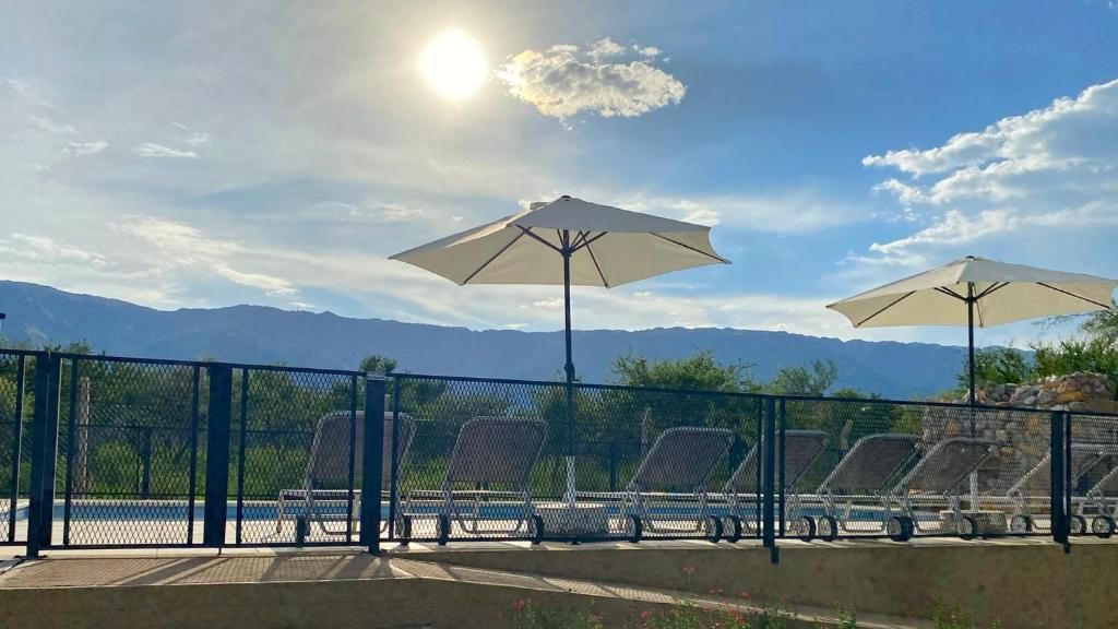 A fenced outdoor seating area with chairs and umbrellas, overlooking a mountainous landscape.