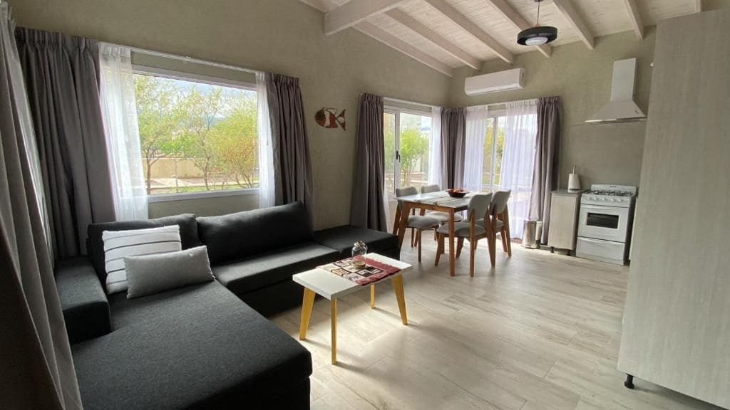 A living room with a sofa, coffee table, and dining area with chairs and a table.
