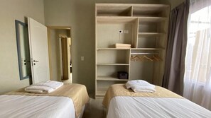 A hotel room with two beds, a walk-in closet, and a window with curtains. - Morada del Cóndor - Cabañas Serranas (Merlo)
