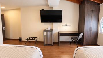Habitación de hotel con dos camas, un escritorio, televisión, minibar y armario.