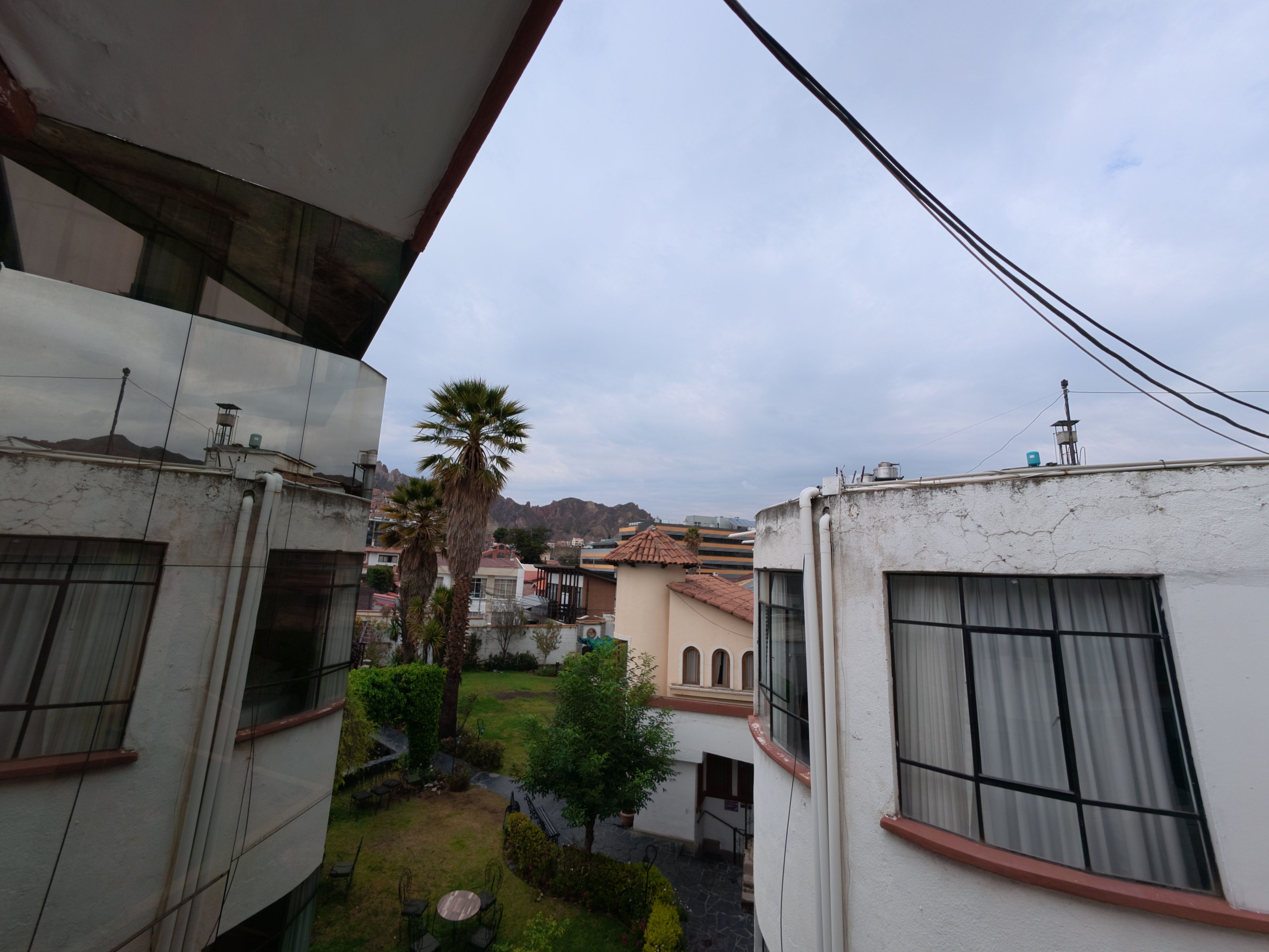 Un patio con una palmera, un pequeño jardín y vistas a un paisaje montañoso.