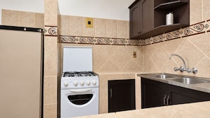 A kitchen with a gas stove, oven, and a sink. - Hotel Calacoto (La Paz)
