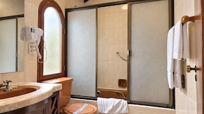 A bathroom with a sink, mirror, and a shower with a glass door. - Hotel Calacoto (La Paz)