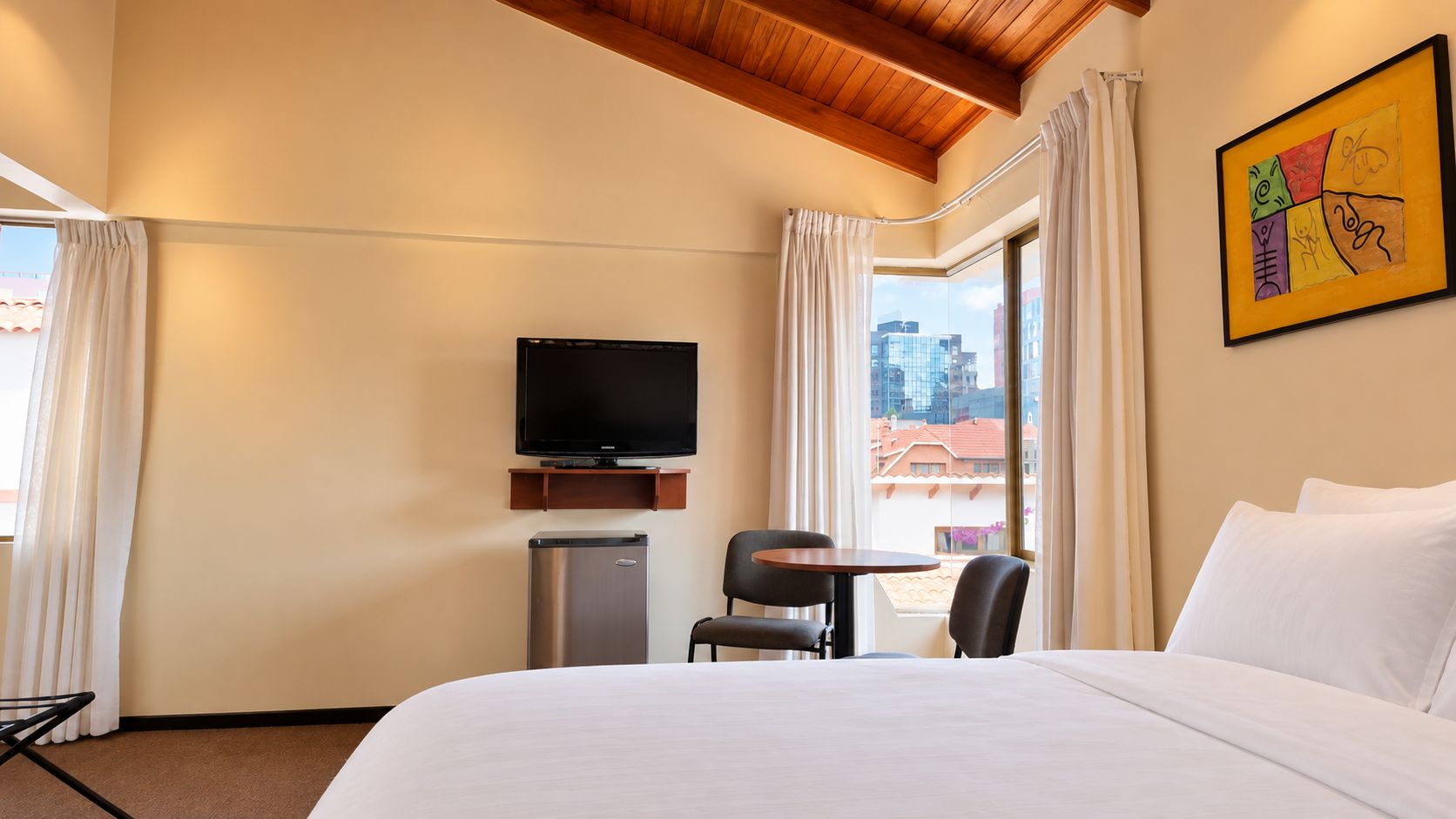 Una habitación de hotel con cama, televisión, escritorio y silla.