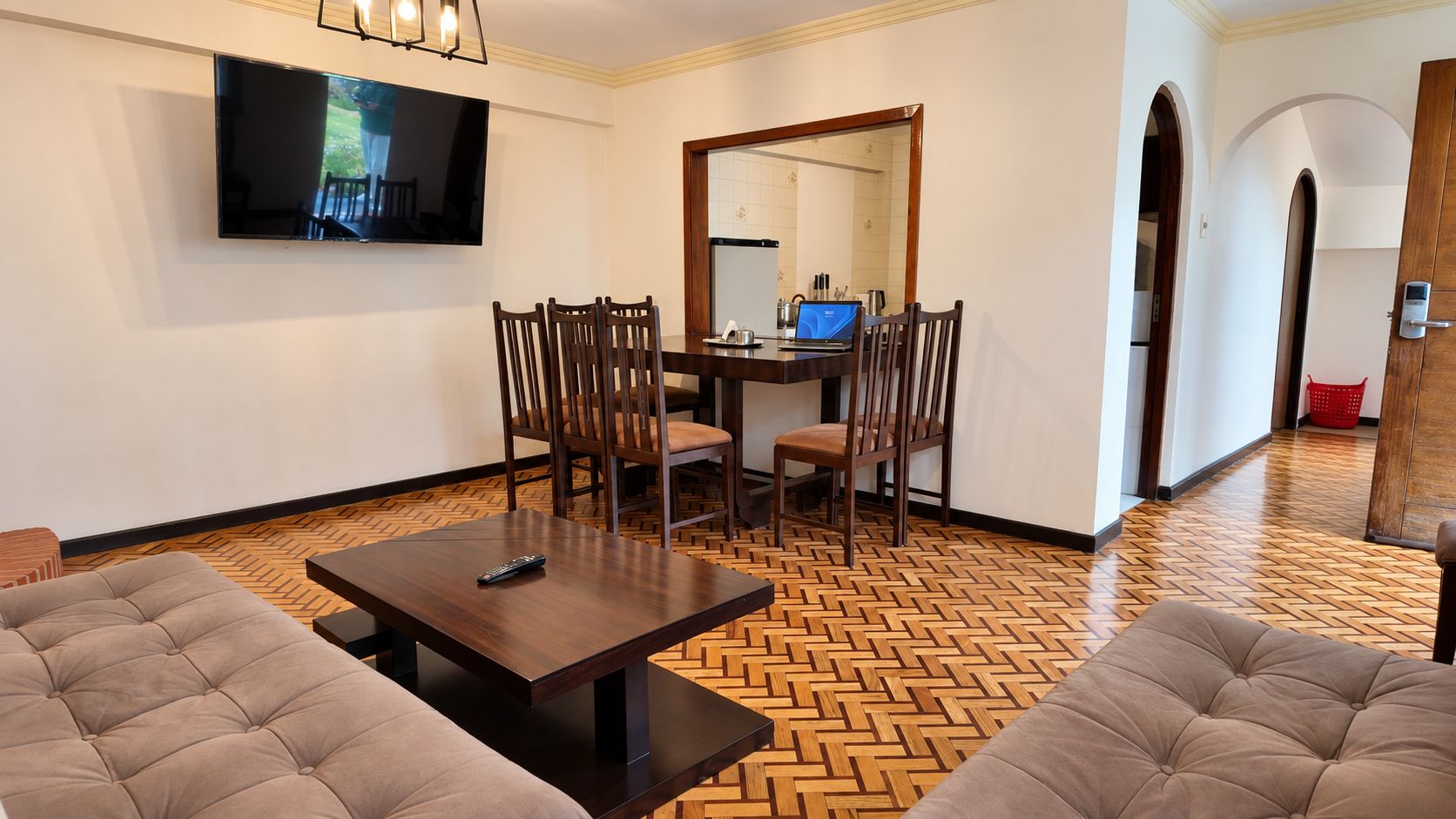 Una sala de estar con televisor, una mesa de comedor con sillas y un sofá.