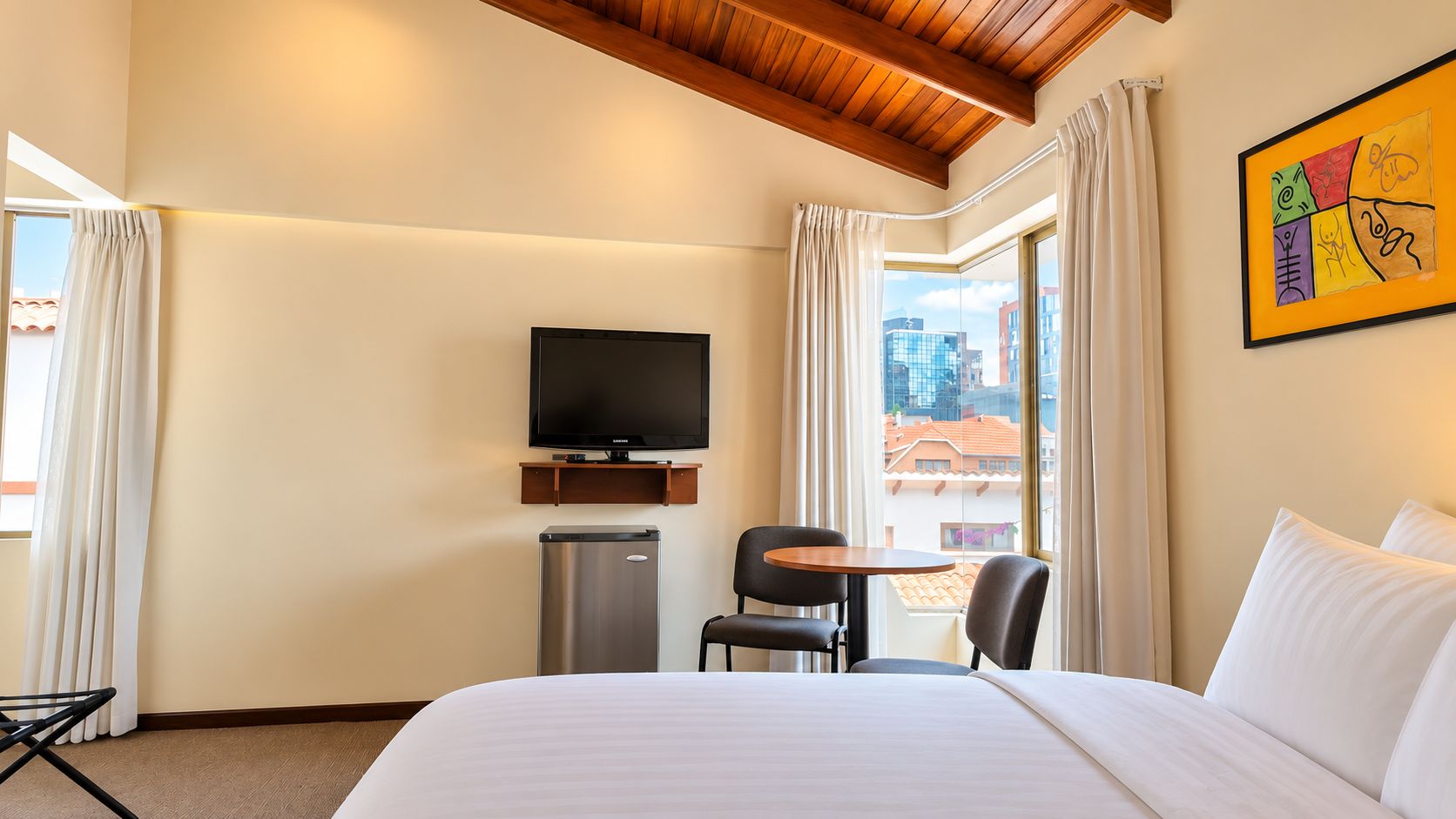 A hotel room with a bed, a television, a desk, and a chair.