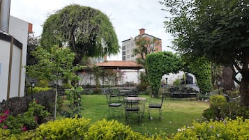 Un jardín con un porche, mobiliario exterior y una diversidad de plantas.