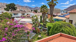 A residential area with houses, a garden with pink flowers, and a mountain backdrop. - Hotel Calacoto (La Paz)