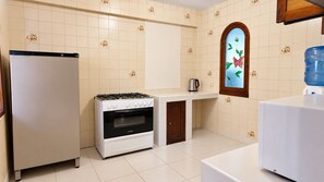 A kitchen with a refrigerator, stove, oven, and a water dispenser. - Hotel Calacoto (La Paz)