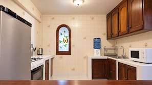 Una cocina equipada con refrigerador, estufa, microondas y dispensador de agua.