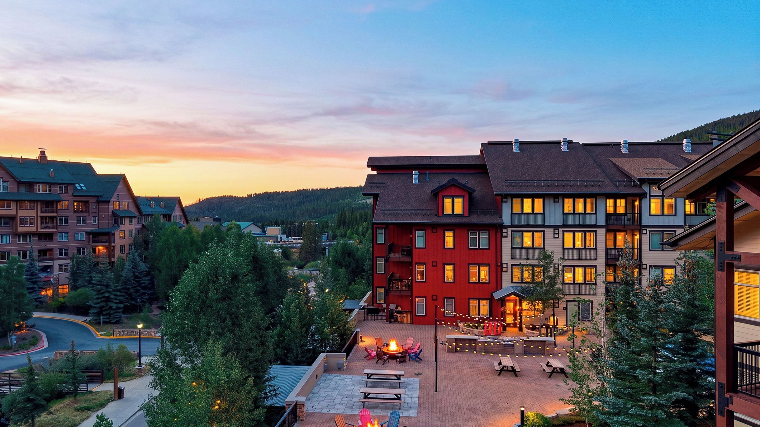 Ein mehrstöckiges Hotel mit einer Terrassenfläche, die Sitzgelegenheiten im Freien und eine Feuerstelle bietet.