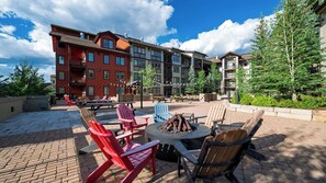 An outdoor patio with Adirondack chairs, a fire pit, and a brick floor. - Little Moose by Avantstay Steps To Winter Park Gondola Shared Hot Tub + Pool (Winter Park)