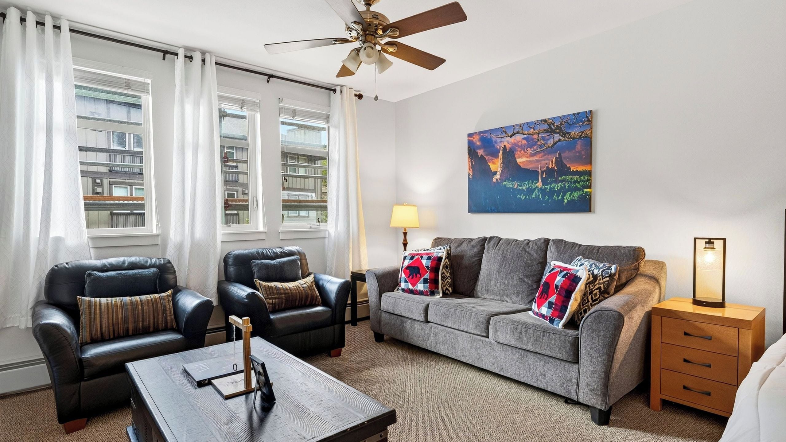 A living room with a sofa, two armchairs, a coffee table, a lamp, and a painting on the wall.