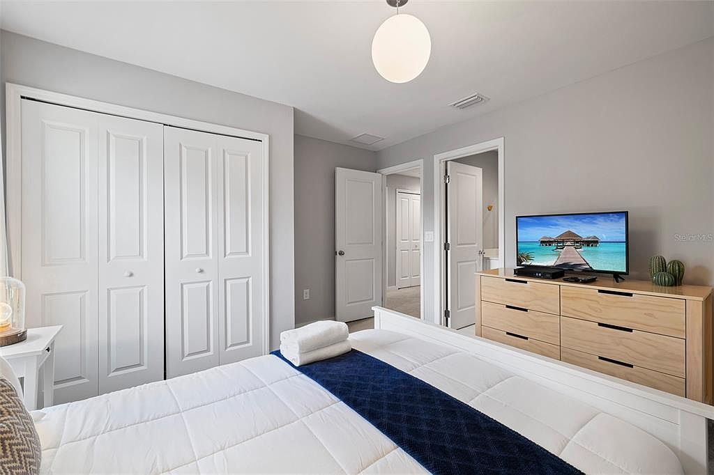 Ein Schlafzimmer mit einem Bett, einem Fernseher, einem Schminktisch und einem Kleiderschrank.