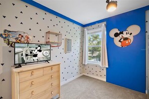 A child's room with a large Mickey Mouse mural, a television, and a window with curtains. - Magical 4BR Home Mickey & Star Wars Rooms Pool (Kissimmee)