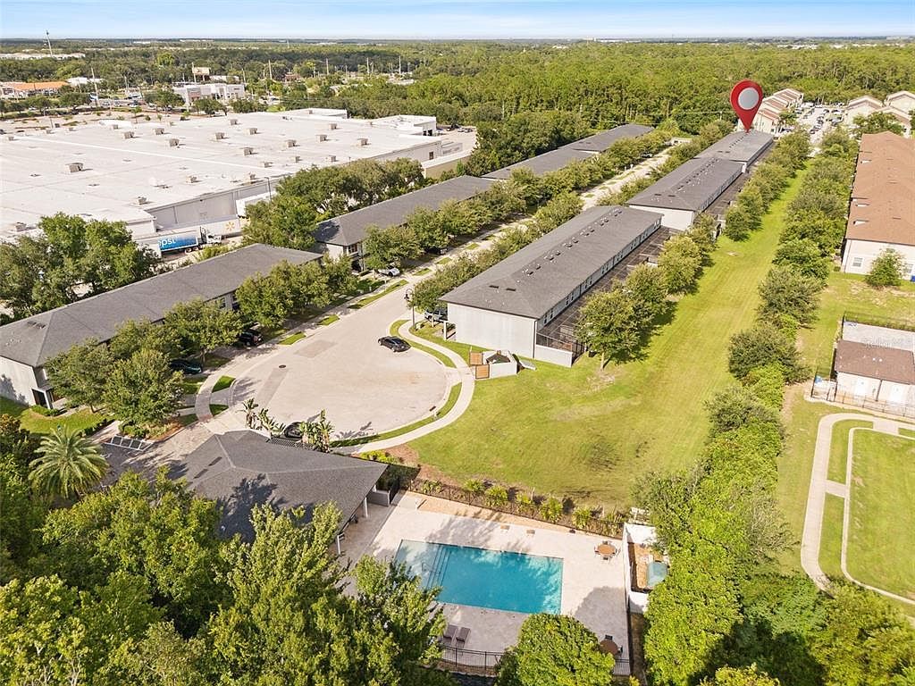 An aerial view of a commercial property with multiple buildings, a parking lot, and a swimming pool.