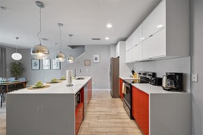 A modern kitchen with a central island, pendant lights, and built-in appliances. - Magical 4BR Home Mickey & Star Wars Rooms Pool (Kissimmee)