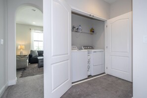 A laundry room with a washing machine, dryer, and shelves with cleaning supplies. - Resort Water Park, 20 Min to LEGOLAND (Haines City)