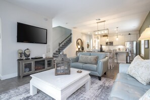 A modern living room with a flat-screen TV, a staircase, a dining area, and a kitchen with a BISTRO sign. - Resort Water Park, 20 Min to LEGOLAND (Haines City)